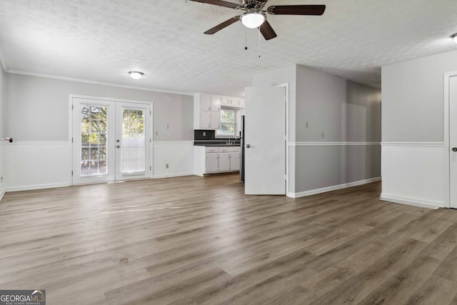 unfurnished living room featuring french doors, hardwood / wood-style floors, a textured ceiling, ceiling fan, and crown molding