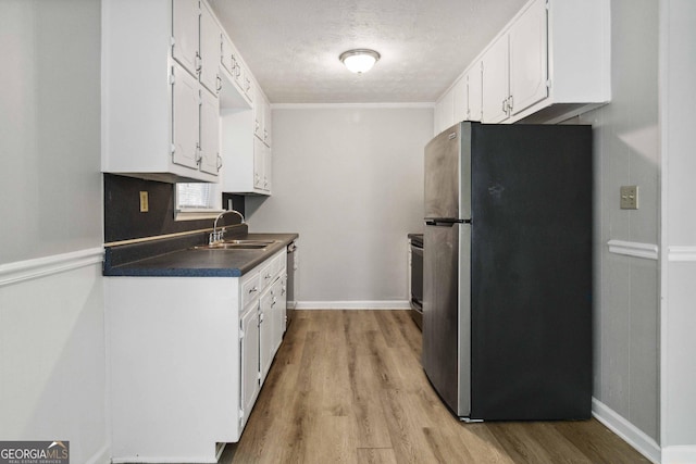 117 Neal Ave, Stockbridge, GA 30281 - kitchen featuring freestanding refrigerator, a sink, wood finished floors, white cabinetry, and a textured ceiling