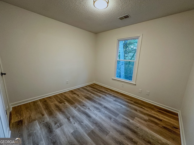 empty room featuring hardwood / wood-style flooring and a textured ceiling