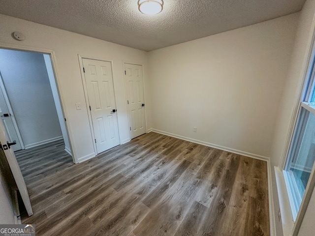 unfurnished bedroom with a textured ceiling and dark hardwood / wood-style floors