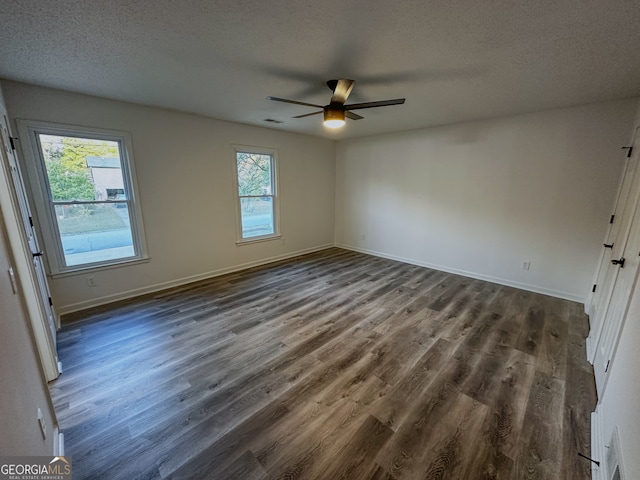 unfurnished room featuring a textured ceiling, dark hardwood / wood-style floors, a wealth of natural light, and ceiling fan