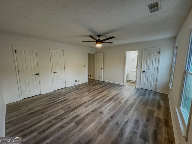 unfurnished bedroom featuring a textured ceiling, ceiling fan, dark hardwood / wood-style floors, and ensuite bathroom