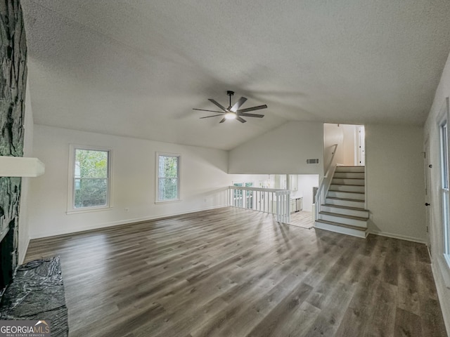 unfurnished living room with a textured ceiling, vaulted ceiling, ceiling fan, a fireplace, and hardwood / wood-style floors