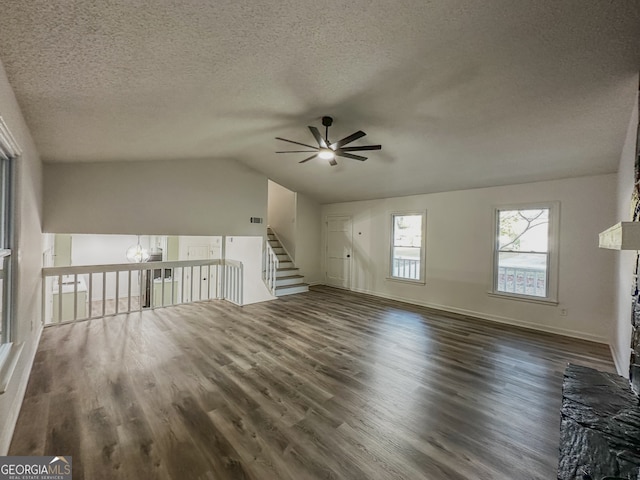 unfurnished living room with a textured ceiling, vaulted ceiling, ceiling fan, and dark wood-type flooring