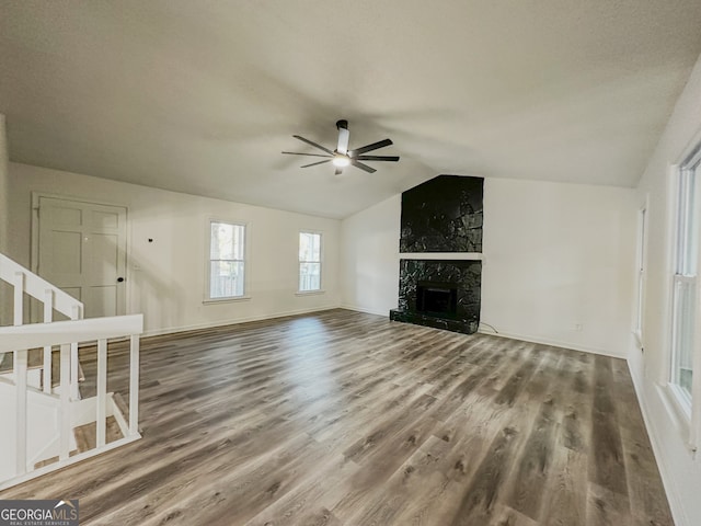 unfurnished living room featuring hardwood / wood-style flooring, ceiling fan, lofted ceiling, and a fireplace