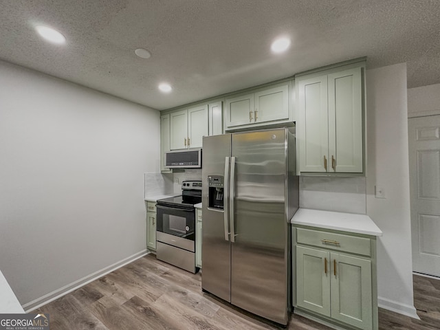 kitchen featuring appliances with stainless steel finishes, a textured ceiling, light hardwood / wood-style flooring, and green cabinets