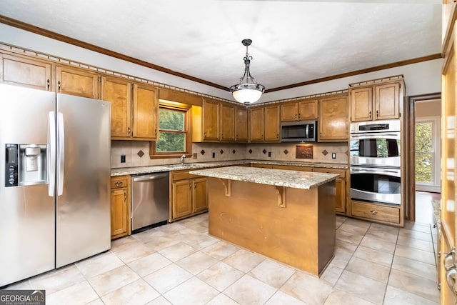 kitchen featuring stainless steel appliances, hanging light fixtures, decorative backsplash, a breakfast bar, and a center island