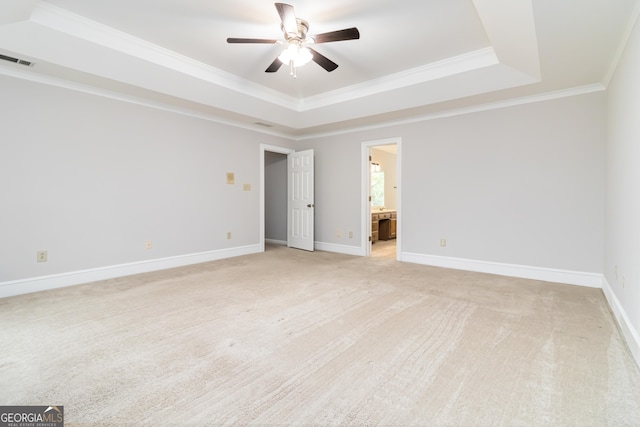 carpeted spare room with ceiling fan, crown molding, and a raised ceiling