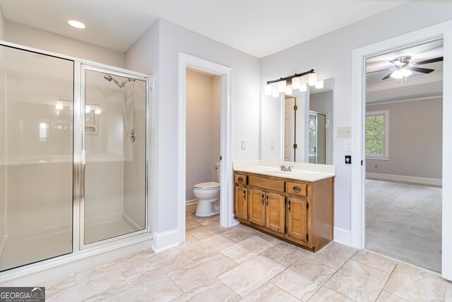 bathroom with toilet, vanity, a shower with door, and ceiling fan