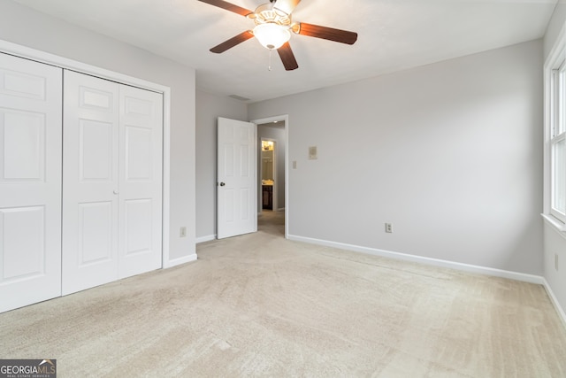 unfurnished bedroom with multiple windows, light carpet, ceiling fan, and a closet