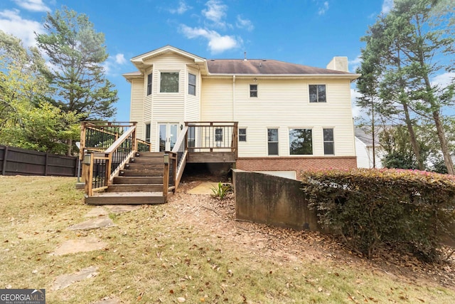 back of house featuring a lawn and a deck