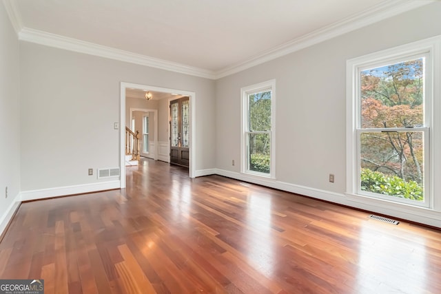 empty room with dark wood-type flooring, a healthy amount of sunlight, and ornamental molding