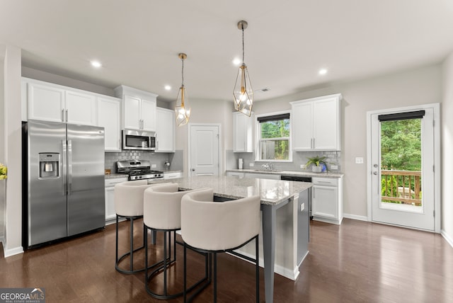 kitchen with white cabinets, a center island, pendant lighting, and appliances with stainless steel finishes