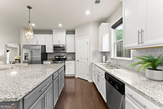 kitchen with white cabinets, sink, dark hardwood / wood-style floors, light stone countertops, and appliances with stainless steel finishes