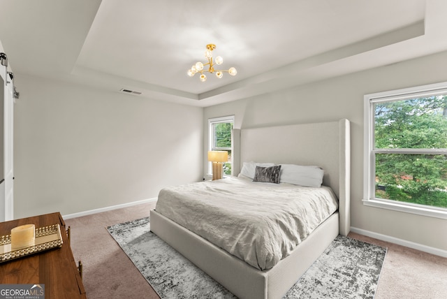 bedroom with an inviting chandelier, a raised ceiling, and multiple windows