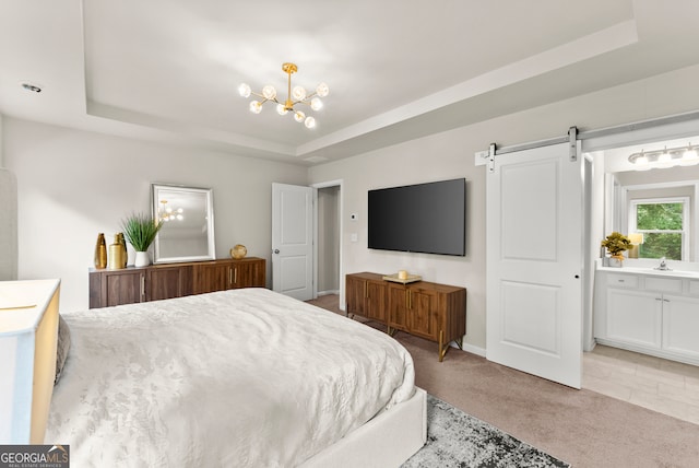 bedroom featuring ensuite bath, a tray ceiling, light colored carpet, a barn door, and a chandelier