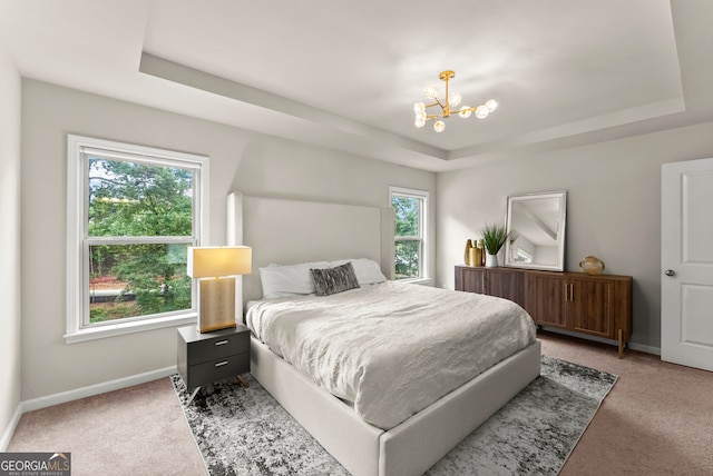 bedroom featuring a notable chandelier, carpet floors, a tray ceiling, and multiple windows