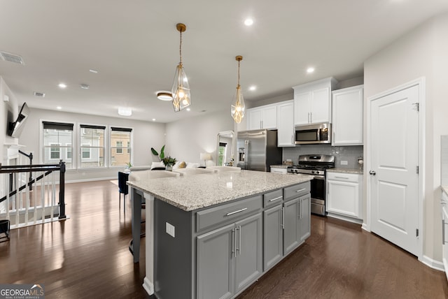 kitchen featuring dark hardwood / wood-style flooring, a center island, stainless steel appliances, and decorative light fixtures