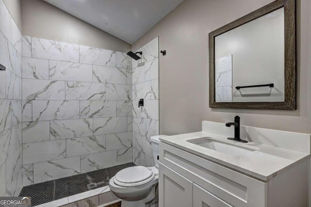 bathroom featuring vanity, toilet, tiled shower, and vaulted ceiling