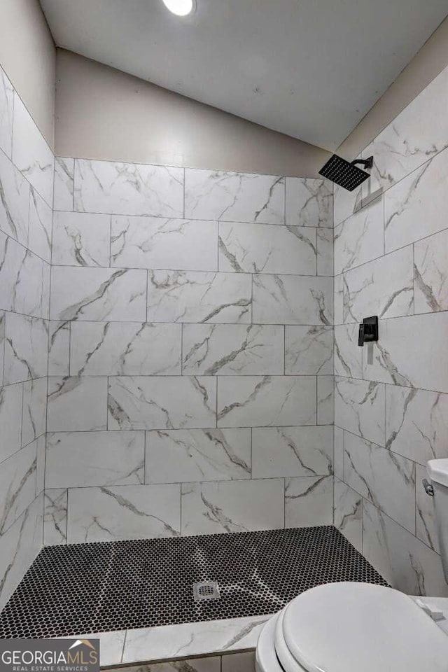 bathroom with a tile shower and toilet