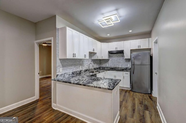 kitchen with dark wood-type flooring, dark stone countertops, white cabinetry, and appliances with stainless steel finishes