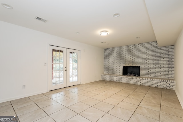 unfurnished living room featuring a brick fireplace, light tile patterned flooring, and french doors