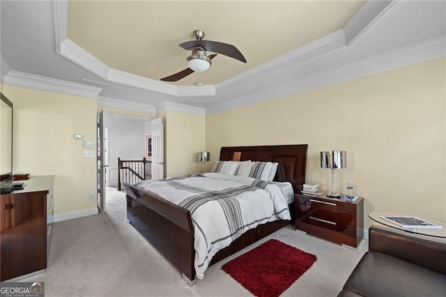 bedroom with ornamental molding, light carpet, ceiling fan, and a tray ceiling