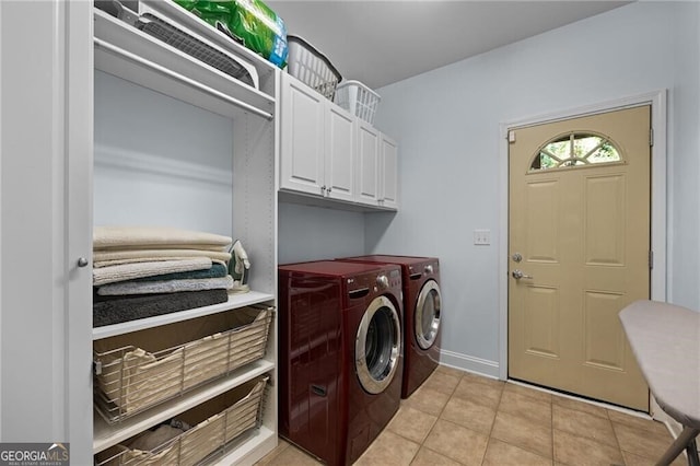 clothes washing area with washer and clothes dryer, cabinets, and light tile patterned flooring