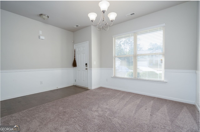 carpeted spare room featuring plenty of natural light and a chandelier