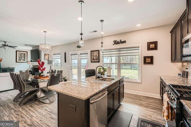 kitchen featuring stainless steel appliances, wood-type flooring, dark brown cabinetry, sink, and a kitchen island with sink