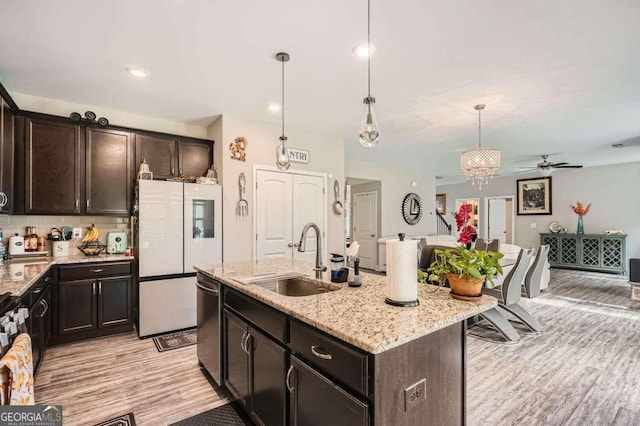 kitchen featuring light hardwood / wood-style floors, sink, an island with sink, hanging light fixtures, and white refrigerator