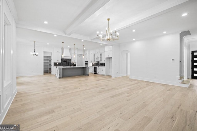 unfurnished living room featuring light hardwood / wood-style floors, beamed ceiling, and an inviting chandelier