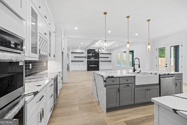 kitchen featuring pendant lighting, gray cabinets, light hardwood / wood-style flooring, and sink