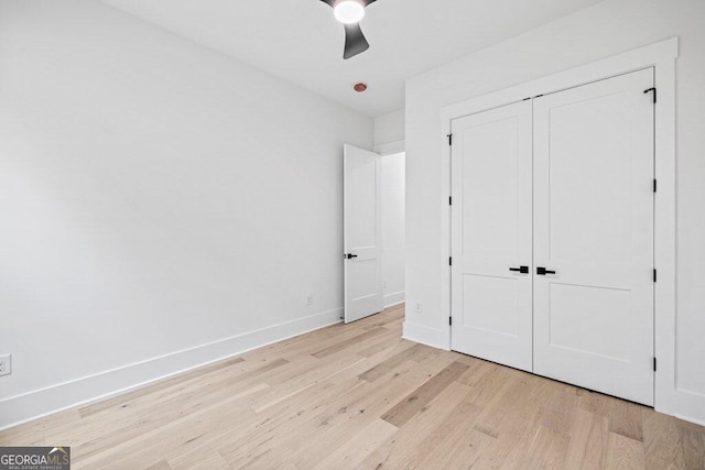 unfurnished bedroom featuring light hardwood / wood-style flooring, ceiling fan, and a closet