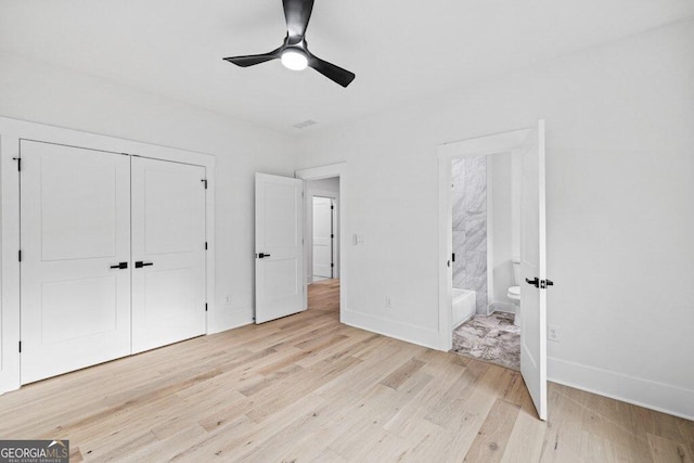 unfurnished bedroom featuring ensuite bathroom, light hardwood / wood-style floors, ceiling fan, and a closet