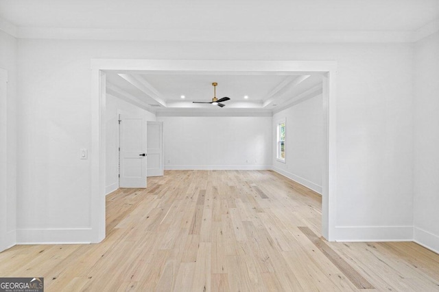 unfurnished room with light wood-type flooring, a tray ceiling, and ornamental molding