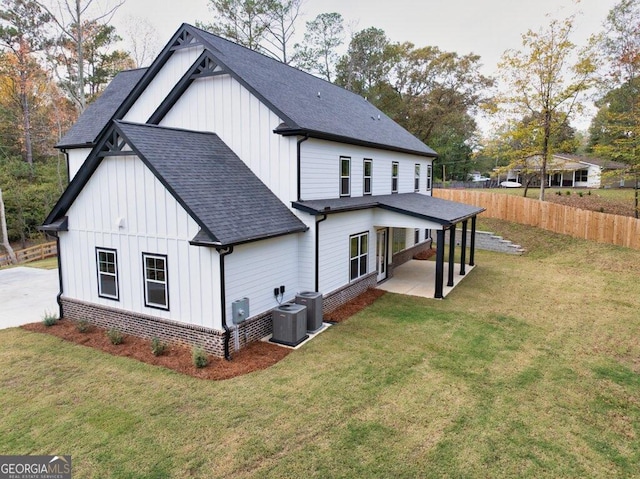 rear view of house with central AC unit, a patio area, and a yard