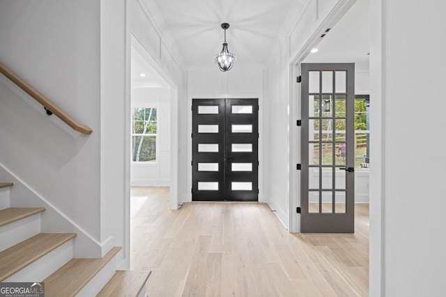 foyer entrance featuring a chandelier, french doors, and light hardwood / wood-style floors