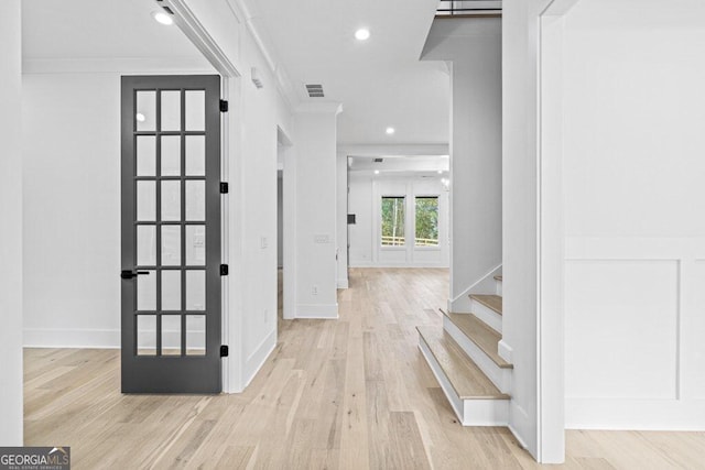 hallway featuring light hardwood / wood-style floors, french doors, and ornamental molding