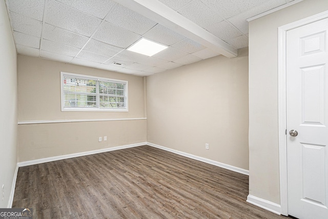 unfurnished room with dark hardwood / wood-style flooring and a paneled ceiling