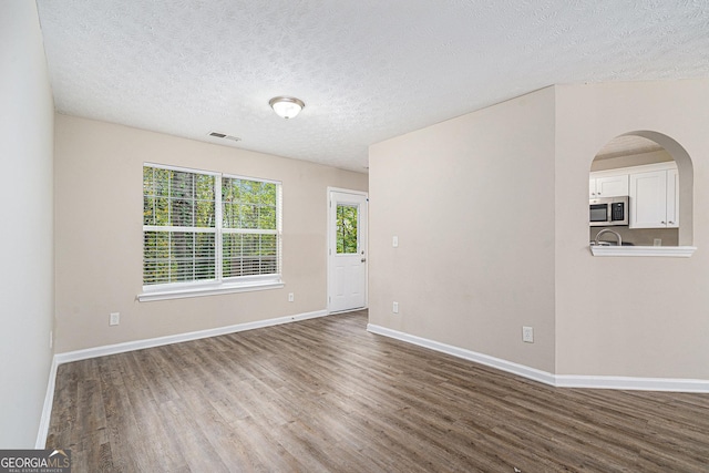 unfurnished room featuring hardwood / wood-style flooring and a textured ceiling