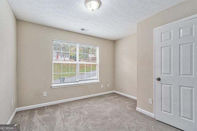 carpeted empty room featuring a textured ceiling