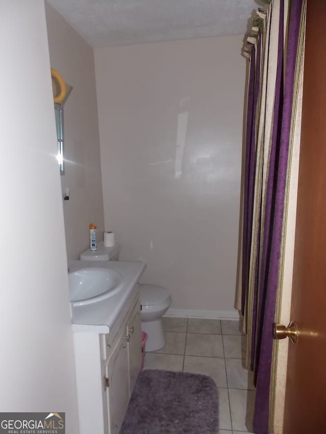 bathroom featuring vanity, tile patterned floors, toilet, and a textured ceiling