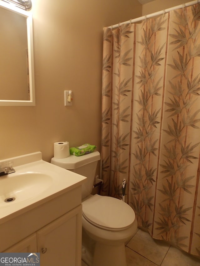 bathroom with toilet, vanity, and tile patterned flooring