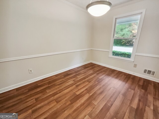 empty room with hardwood / wood-style floors and ornamental molding