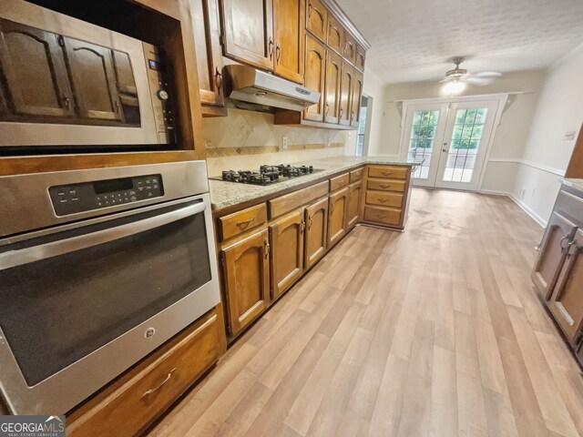 kitchen with french doors, stainless steel appliances, light hardwood / wood-style floors, decorative backsplash, and ceiling fan