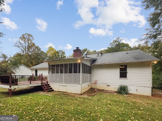 rear view of property with a deck, a sunroom, and a yard