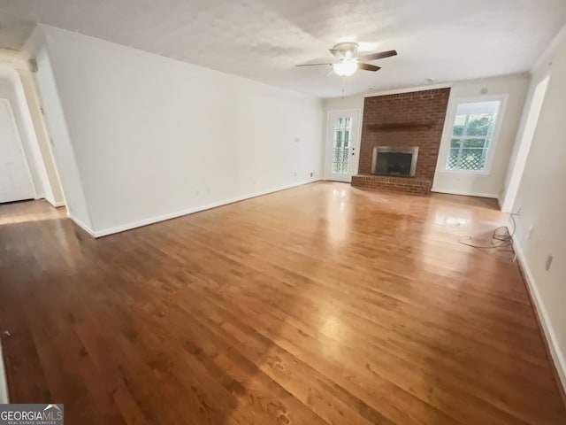 unfurnished living room with hardwood / wood-style floors, ceiling fan, and a brick fireplace