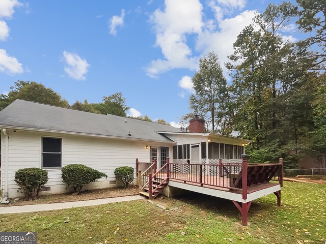 back of property with a deck, a lawn, and a sunroom