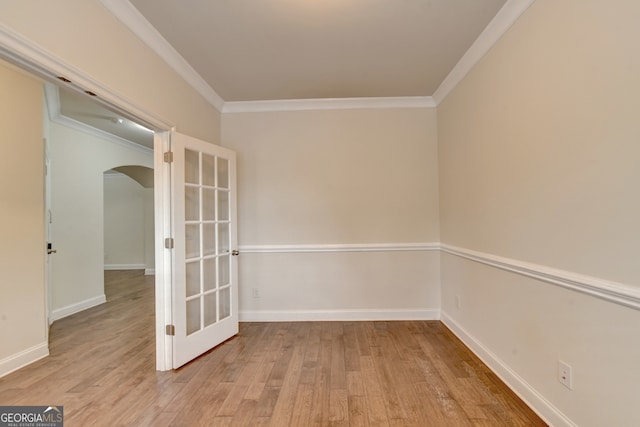 empty room featuring french doors, light hardwood / wood-style floors, and crown molding